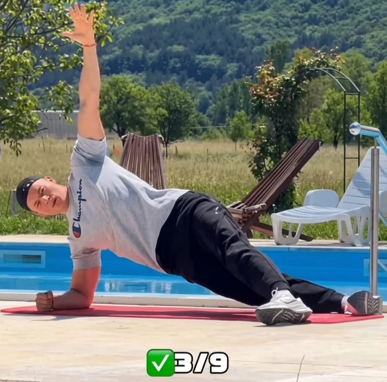 The Sedentary Desk Worker’s Survival Guide: 9 Home Rehab Exercises to Eliminate Lower Back Pain, Anterior Pelvic Tilt, and "Tech Neck" 8 A trainer performing a side plank exercise on a red mat to improve lateral core stability and reduce lower back pain from sitting