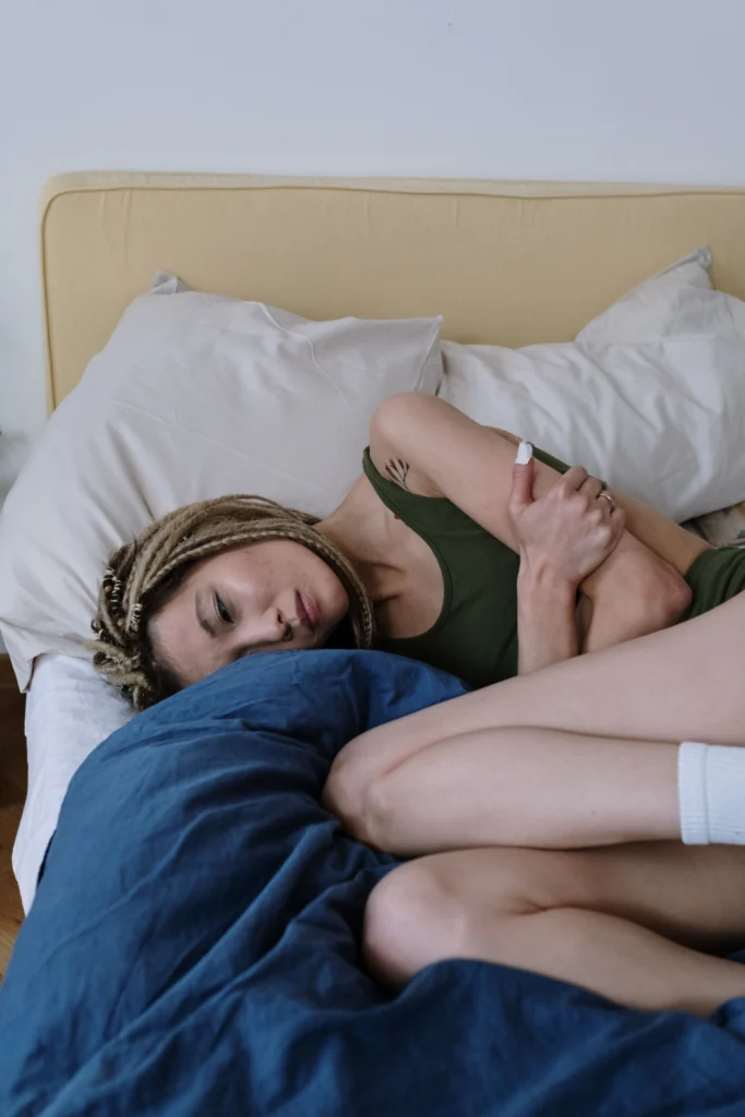 Woman resting in bed dealing with period cramps during fitness for women over 35 routine